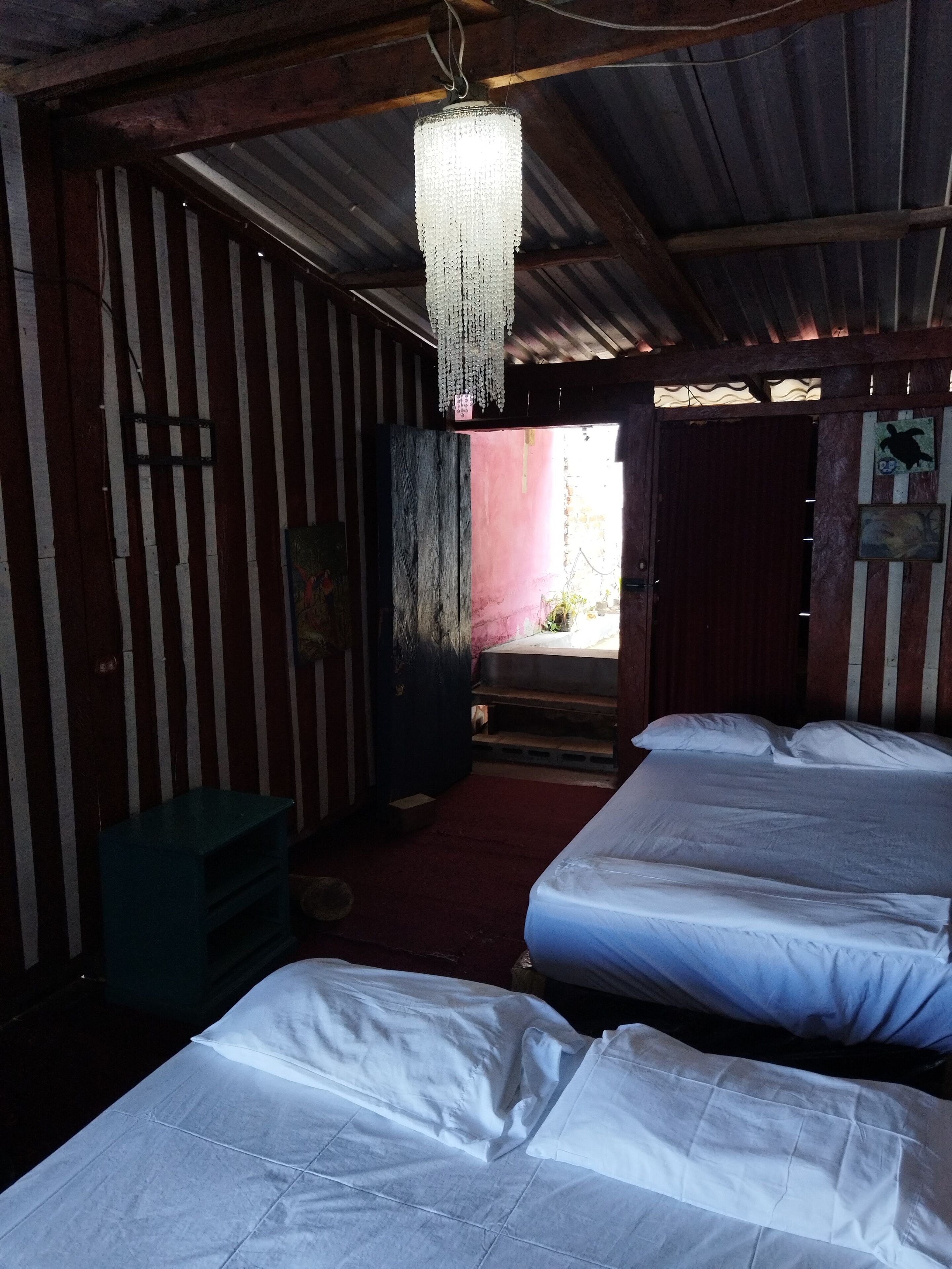 Une chambre avec deux lits, un plafond en bois et un lustre suspendu.