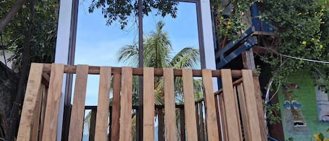 A room with a large window, wooden slats, and a view of palm trees.