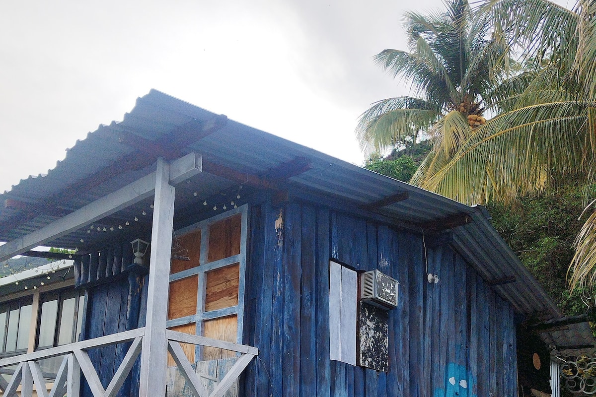 Un edificio rústico de madera con un balcón, una piscina pequeña y un mural en la pared.