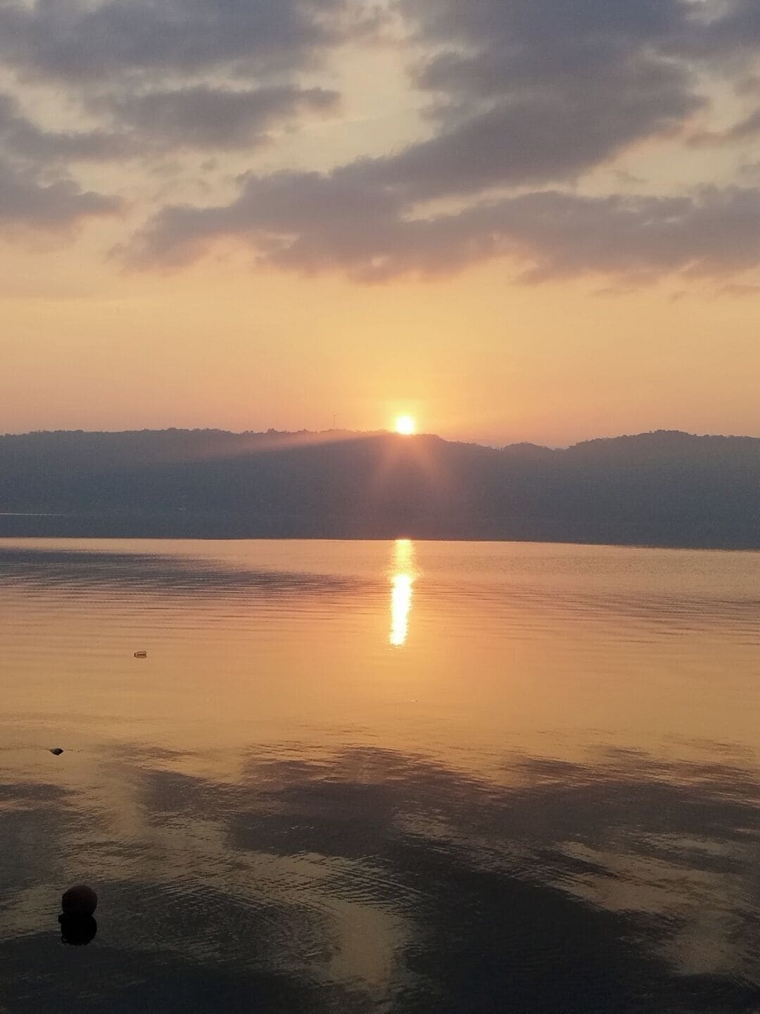 A sunset over a calm body of water with a distant landmass.