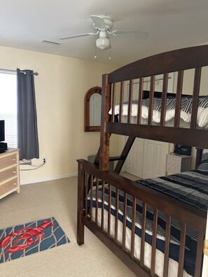 A bedroom with a bunk bed, a ceiling fan, a dresser, and a mirror.