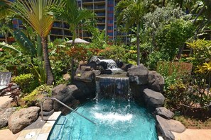 A pool with a waterfall feature surrounded by tropical plants and rocks. - Ka'anapali Shores 160 (Lahaina)