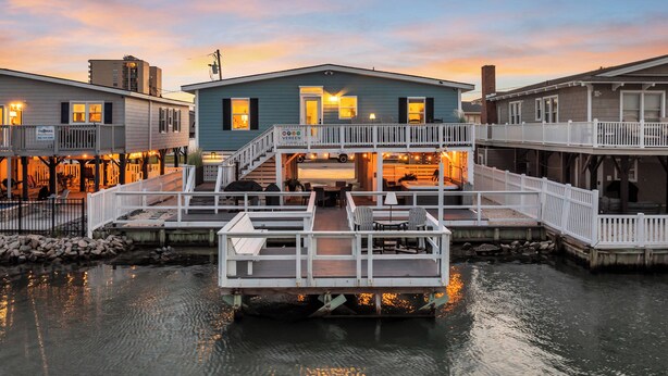 Ein Haus am Wasser mit Anlegesteg, überdachter Sitzgelegenheit und einer Veranda.