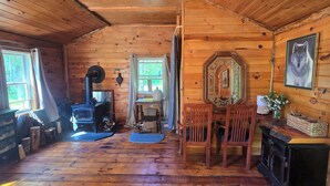 Interior de una cabaña de madera con estufa, dos puertas, un espejo y chimenea.