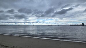 Una playa con mar tranquilo, un muelle y un cielo nublado.