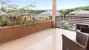 A balcony with wicker furniture, a view of houses, and a clear sky. - Private Cottage in Drax Hall Manor Pool Gym 24hr Secure (Ocho Rios)