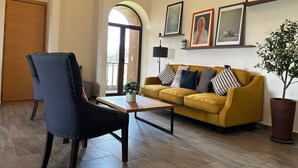 A living room with a sofa, armchair, coffee table, and a potted plant.