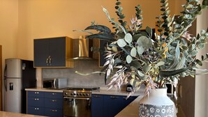 A modern kitchen with dark cabinets, stainless steel appliances, and a decorative plant in a patterned vase.