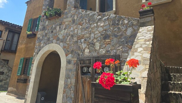 A building with stone walls, a wooden door, and a window with a stone frame.