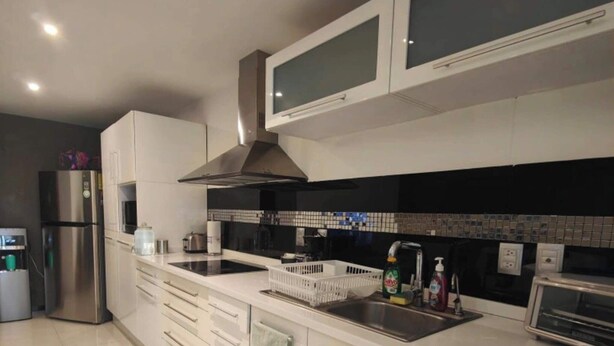 Une cuisine moderne avec des meubles blancs, un réfrigérateur en acier inoxydable, un four à micro-ondes et un grille-pain.