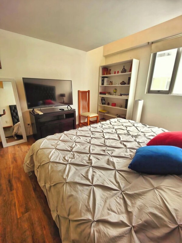 Une chambre à coucher avec un lit, une télévision, une bibliothèque et une fenêtre.