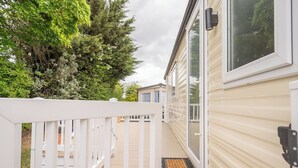Une maison mobile dotée d’une terrasse en bois et d’un paillasson noir.