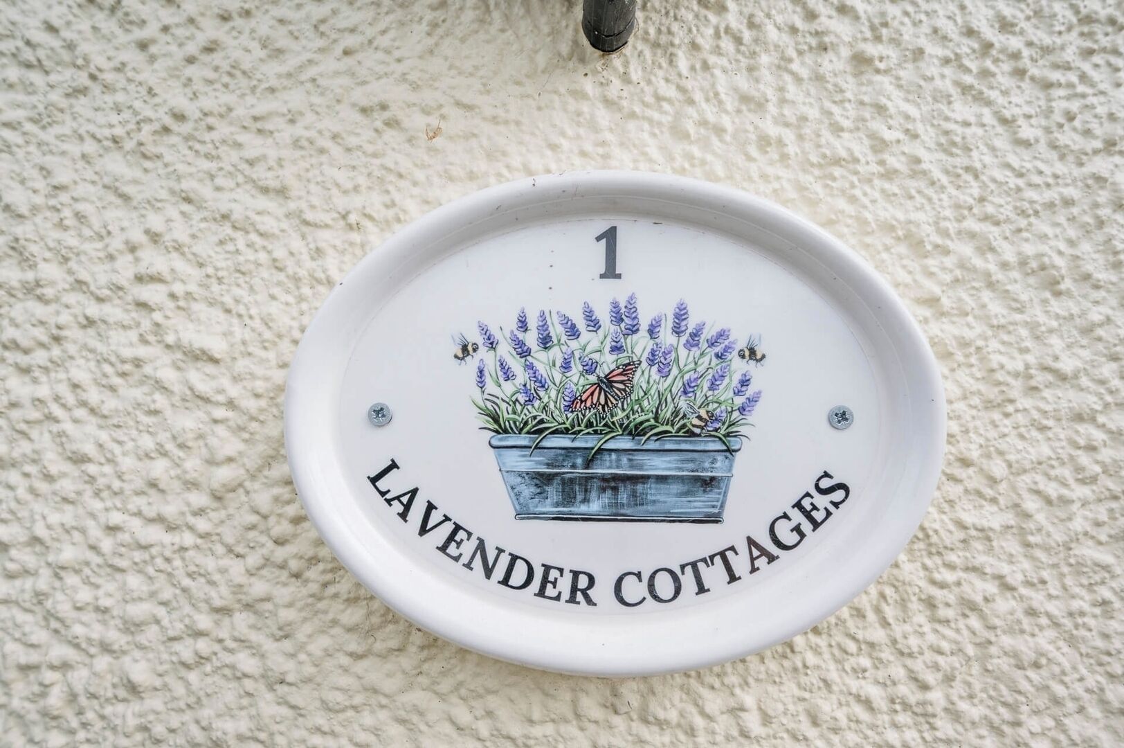Una placa de cerámica blanca con una ilustración de jardín de lavanda y el texto 