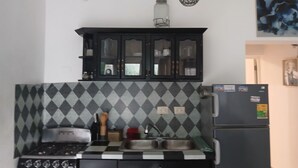 A kitchen with a gas stove, black cabinets, a checkered backsplash, and a refrigerator.