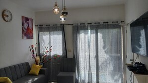 A living room with a sofa, ottoman, and a decorative plant.