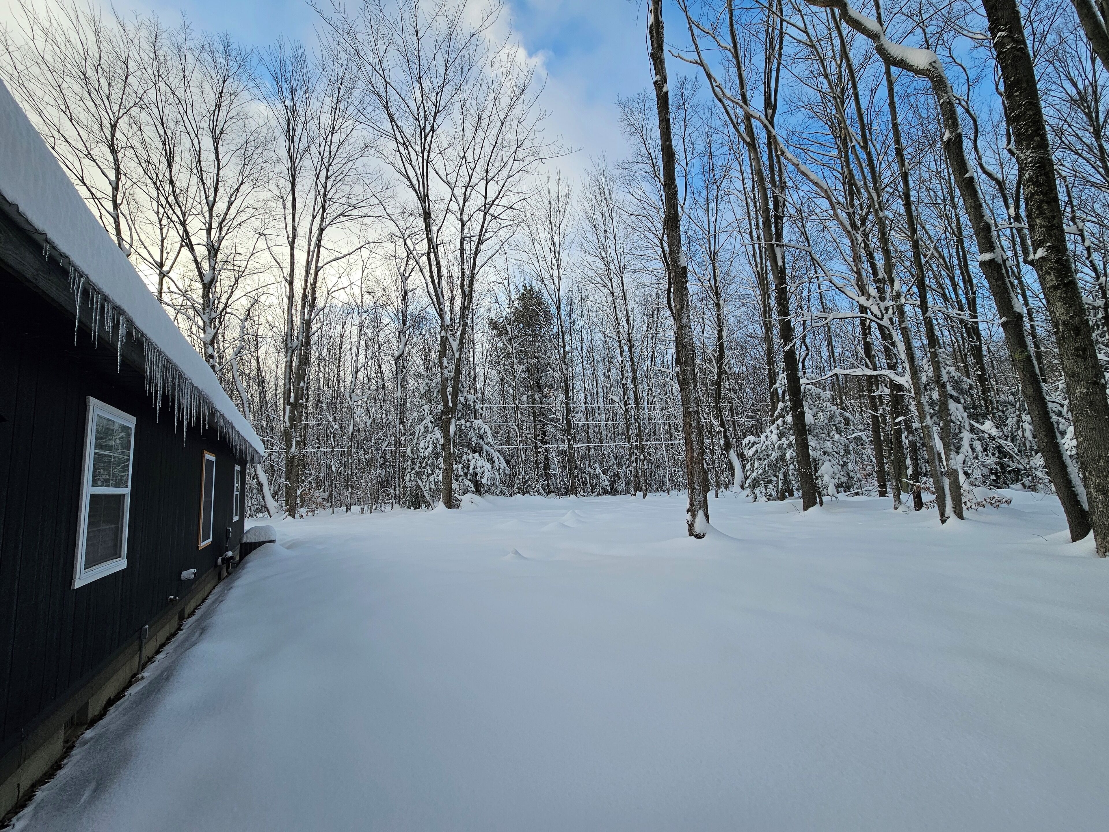 A cabin with a snow-covered roof and a clear sky.