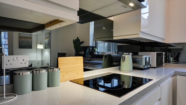 A modern kitchen with a built-in stove, a toaster, and a kettle. - Cosy Wigan Apartment With Sunny Views (Wigan)