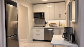 A modern kitchen with white cabinets, stainless steel appliances, and a white countertop.