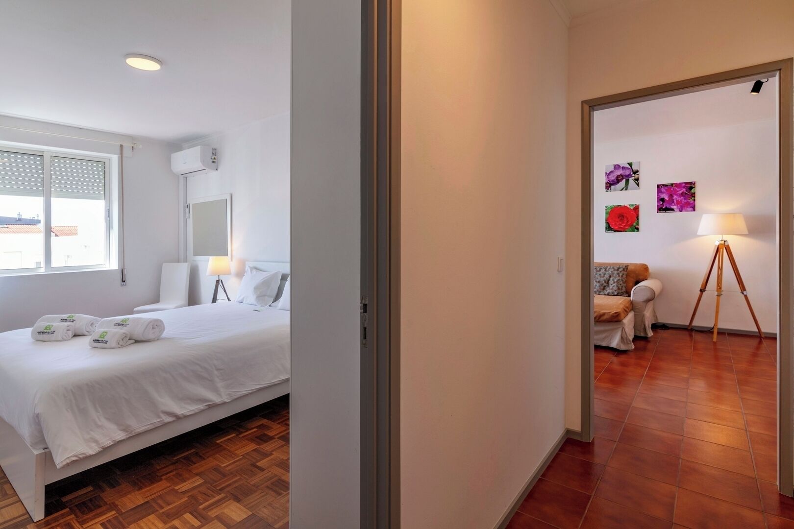 Ein Hotelzimmer mit Bett, Nachttisch, Lampe und Blick ins Freie.