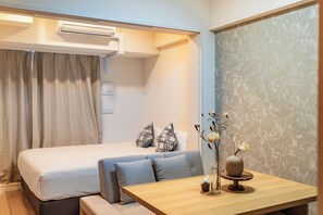 Une chambre d’hôtel avec un lit, un canapé, une table en bois et un vase rempli de fleurs.