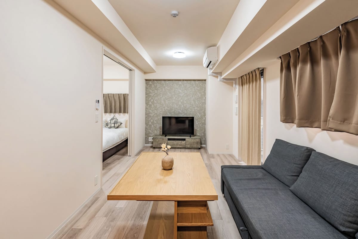 A modern living room with a sofa, a TV, and a wooden coffee table.