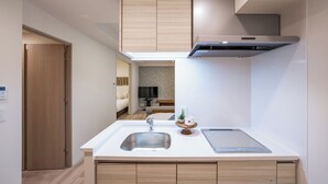 A modern kitchen with a built-in sink, a microwave, and a stove. There is a wooden door and a small plant on the counter.