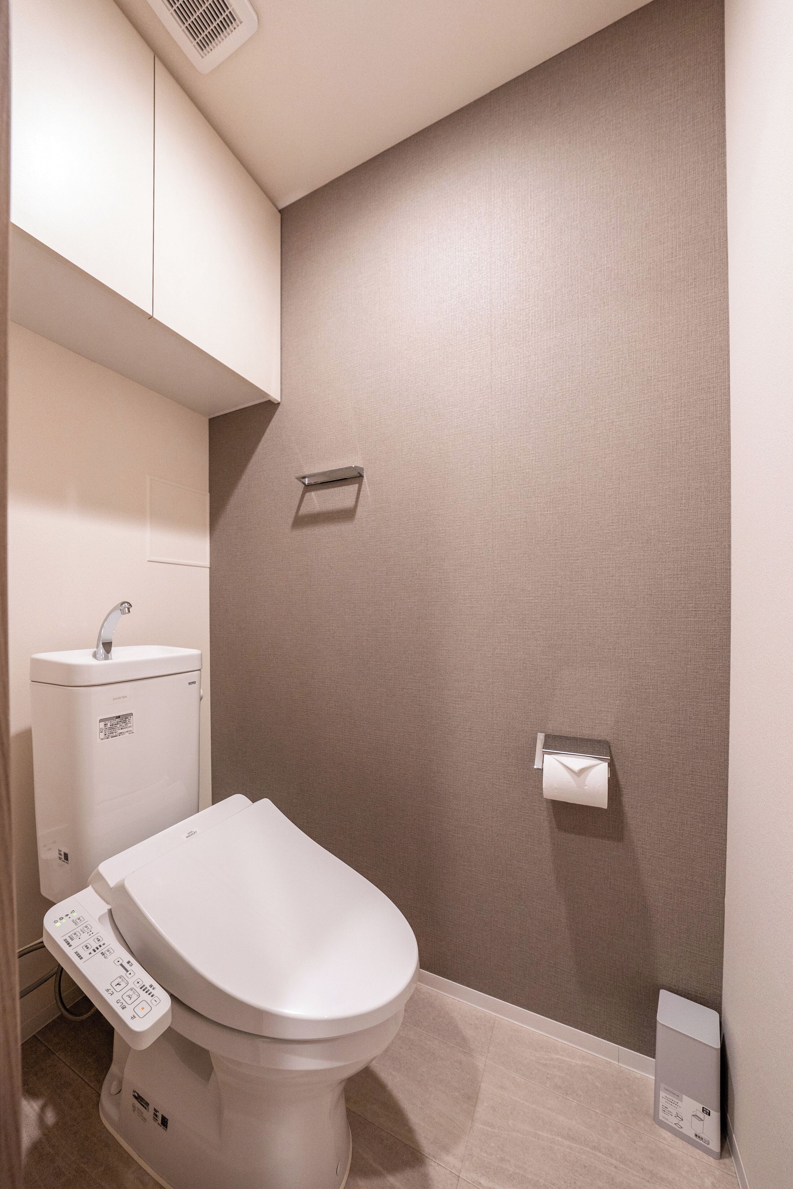 Ein modernes Badezimmer mit Toilette, Waschbecken und Handtuchspender.