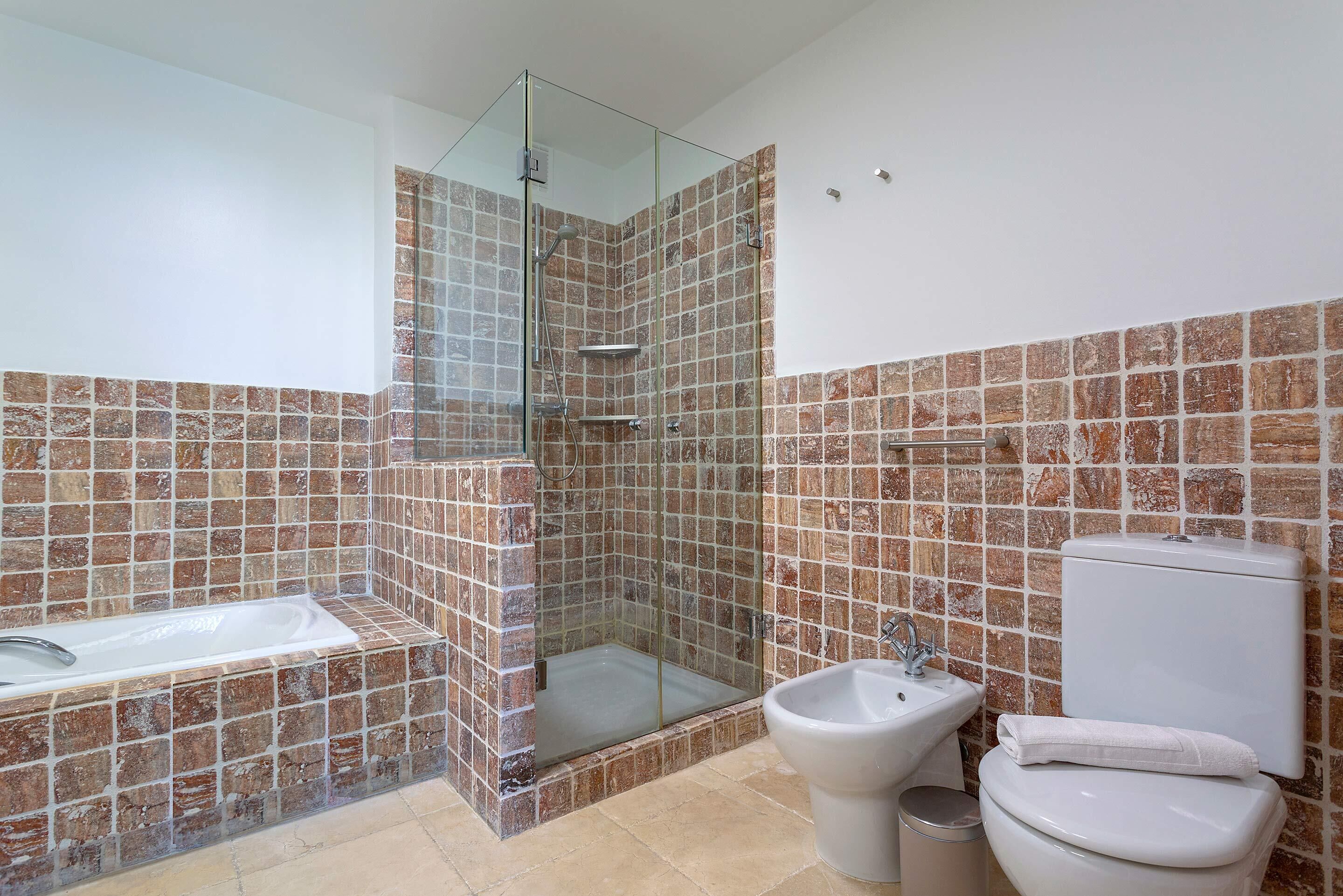A bathroom with a glass-enclosed shower, a bathtub, a bidet, and a toilet.