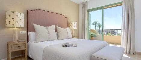 A hotel room with a large bed, two bedside lamps, a nightstand, a window with a view, and a balcony.