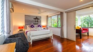 A spacious bedroom with a large bed, a ceiling fan, a view of the outdoors, and a wooden floor.
