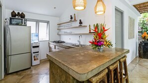 A modern kitchen with a central island, stainless steel appliances, and hanging pendant lights.