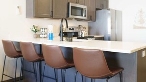 A modern kitchen with a central island, stainless steel appliances, and four brown bar stools. - 2BR/2.5BA 15 Min. Silverwood,  9 Min. Hayden Lake (Hayden)