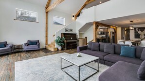 Un'ampia zona giorno con un pianoforte, divani e una scala che conduce a un piano superiore.