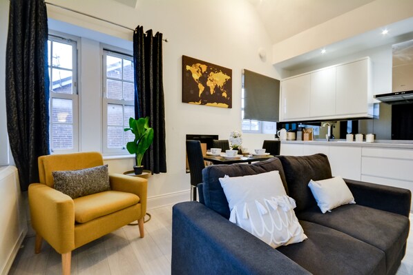 A modern living room with a sofa, armchair, and dining table.