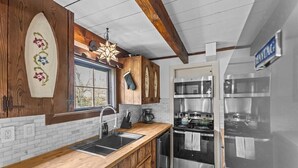 A kitchen with wooden cabinets, a stainless steel refrigerator, a built-in oven, and a window with a view.