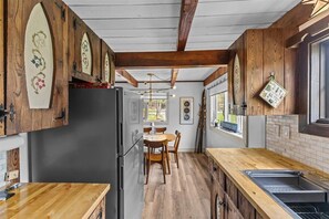 Une cuisine avec des poutres en bois, un réfrigérateur noir, une table à manger en bois et des chaises.
