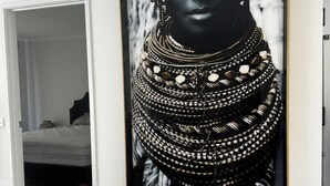 A framed artwork of a person in traditional attire on a white wall. - Coastal Calm (Rye)