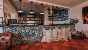 A bar area with a stone wall, bookshelves, and a coffee display. - HOTEL BALCON DEL CIELO  (Dosquebradas)