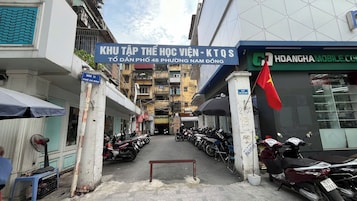 Rua estreita com motocicletas estacionadas e uma placa de prestadora de serviços móveis.