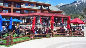 Ein Restaurant mit Außenbestuhlung, einem Holzzaun und einer Bergkulisse.