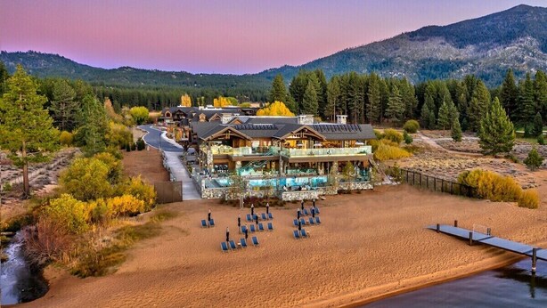 Eine Lodge mit Pool, umgeben von einem Sandstrand und bewaldeten Hügeln.