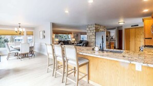 Una cocina moderna con una isla de piedra, taburetes de bar y un comedor con mesa y sillas.