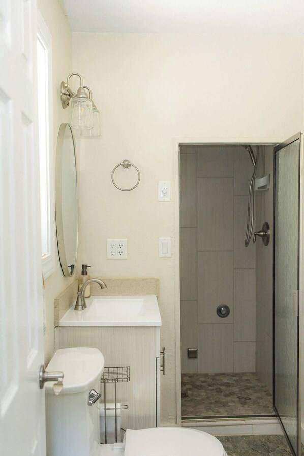 Un baño con inodoro, lavamanos, espejo y ducha.