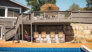 Una casa de dos pisos con balcón, mobiliario exterior y piscina.