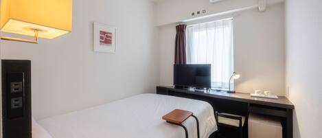 Una habitación de hotel con cama, escritorio, televisor, aire acondicionado y lámpara.