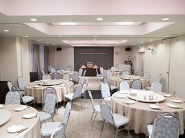 A conference room with multiple round tables, each set with plates, glasses, and cutlery.