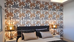 A bedroom with a patterned wallpaper, a bed with multiple pillows, and two bedside lamps. - Vue Mer Panoramique  Confort Moderne (Les Sables-d´Olonne)