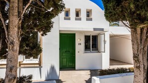 Un edificio blanco con una puerta verde y tres ventanas.