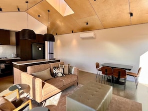 Uma sala de estar moderna com sofá, apoio para os pés e mesa de jantar com cadeiras.