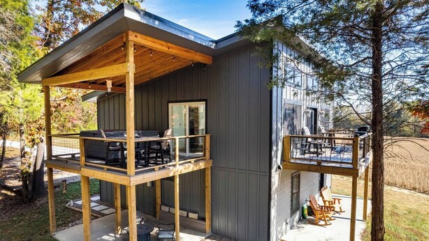 A modern cabin with a wooden deck, a covered outdoor seating area, and a small balcony. - Quiet Country Oasis with Hot Tub (Hardinsburg)